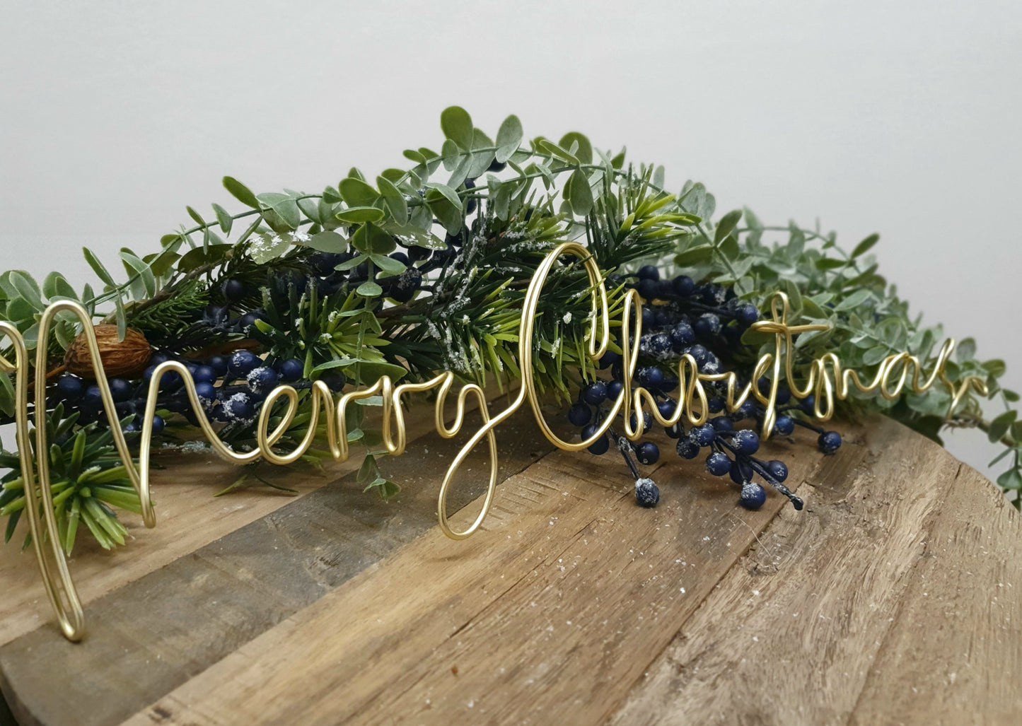 Gold Merry Christmas Wire Word Christmas Wreath Sign for Christmas Decoration as a table centrepiece surrounded by a frosted berry garland