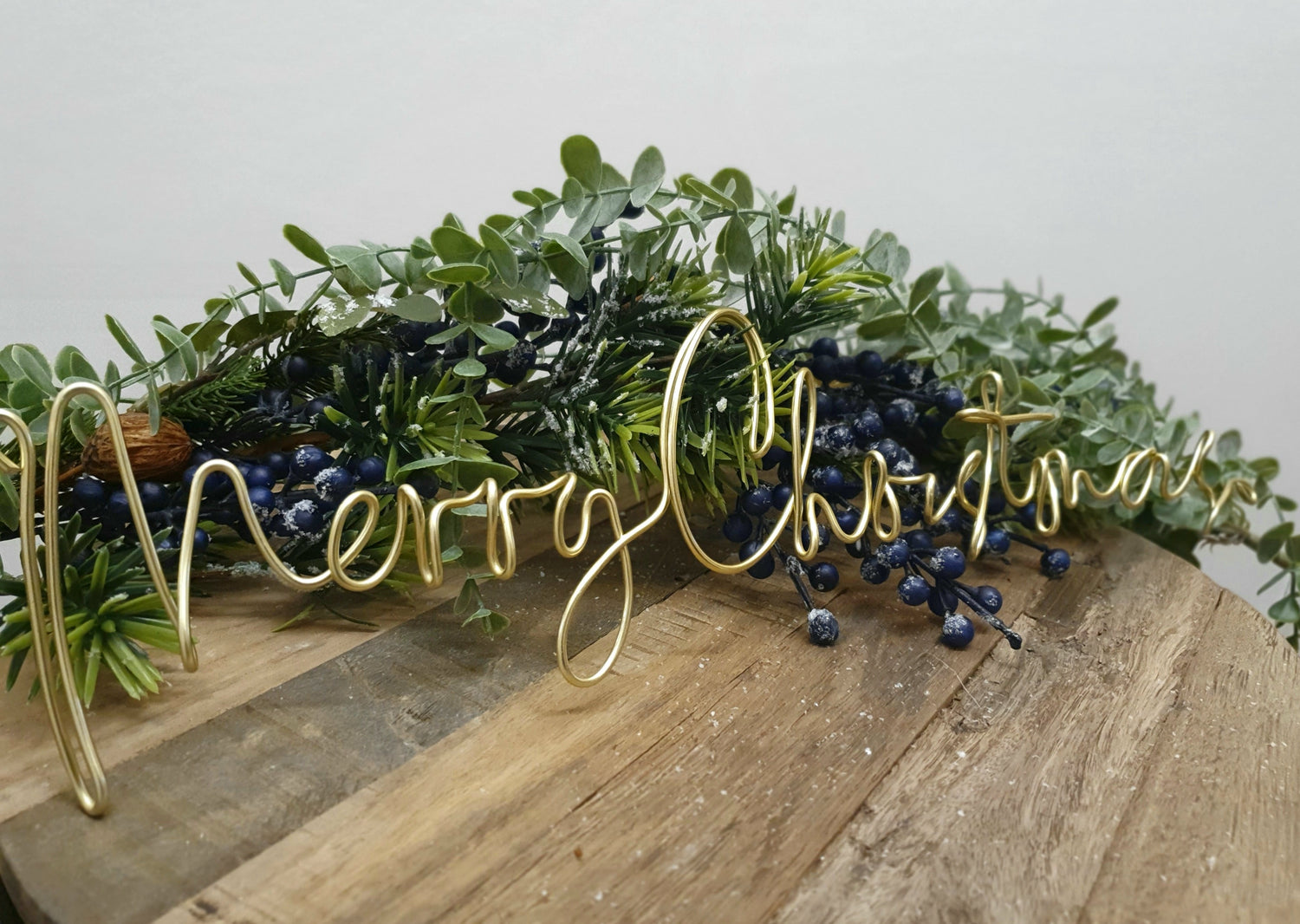 Gold Merry Christmas Wire Word Christmas Wreath Sign for Christmas Decoration as a table centrepiece surrounded by a frosted berry garland