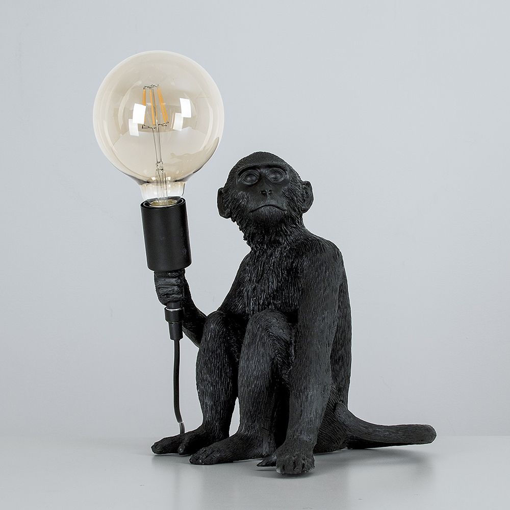 Martha the Monkey Table Lamp in Matte Black Holding A Light Bulb