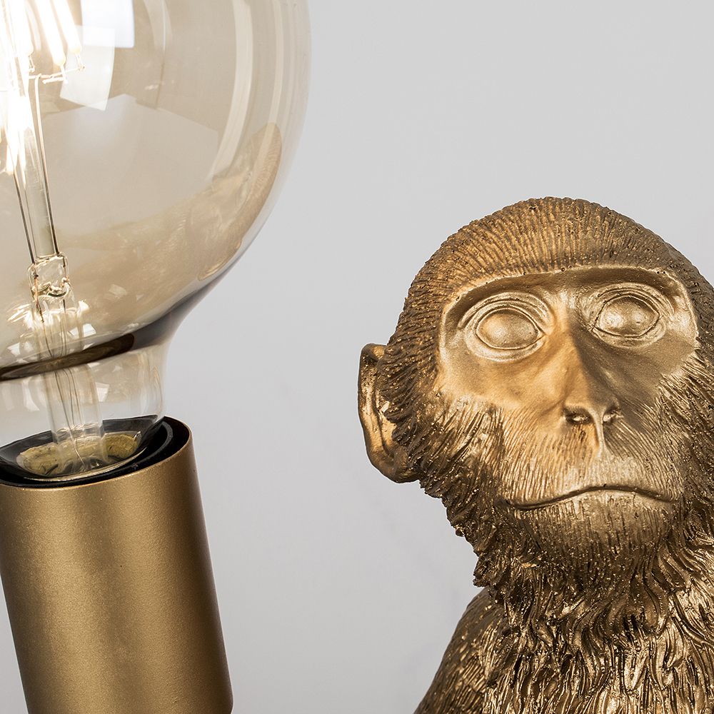 Martha the Monkey Table Lamp in Metallic Gold Holding A Light Bulb