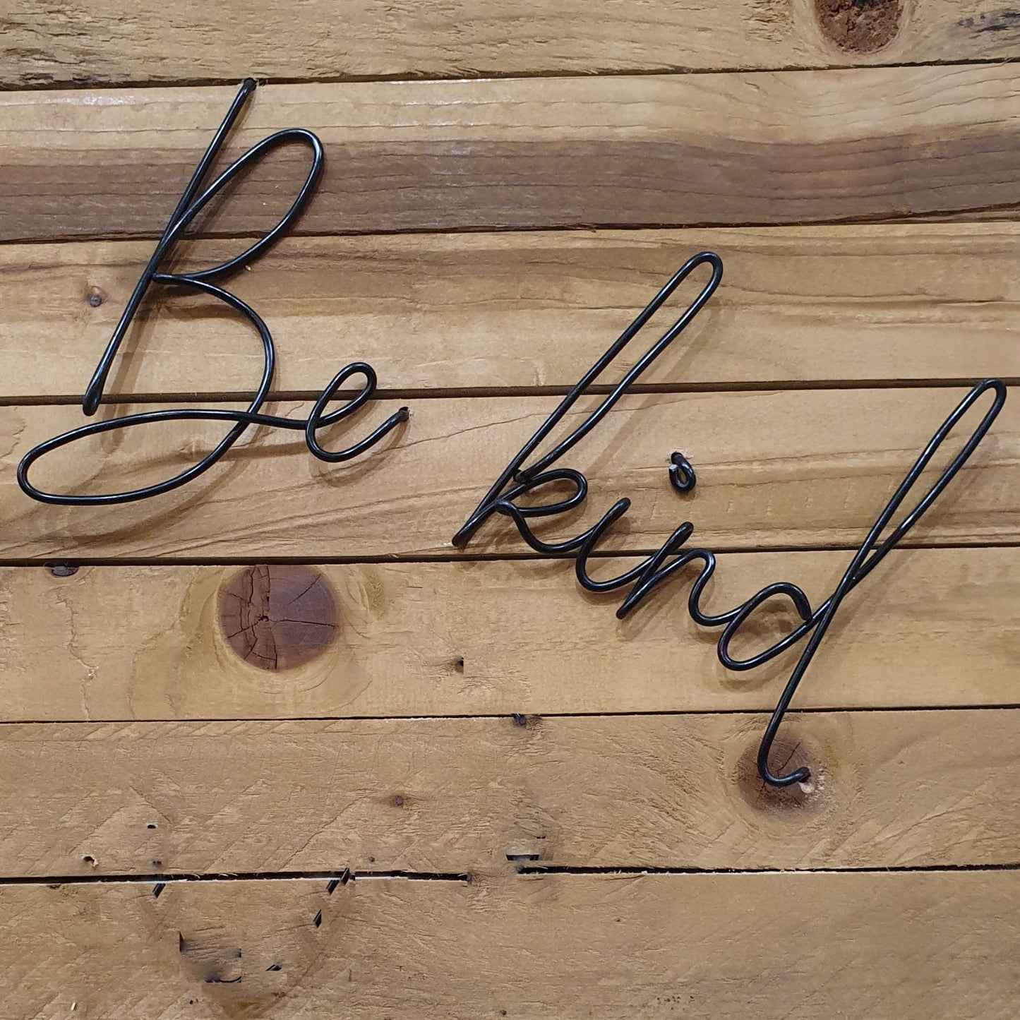 Gold Be Kind Wire Words Wall Art Decoration on a Wood Panel Wall