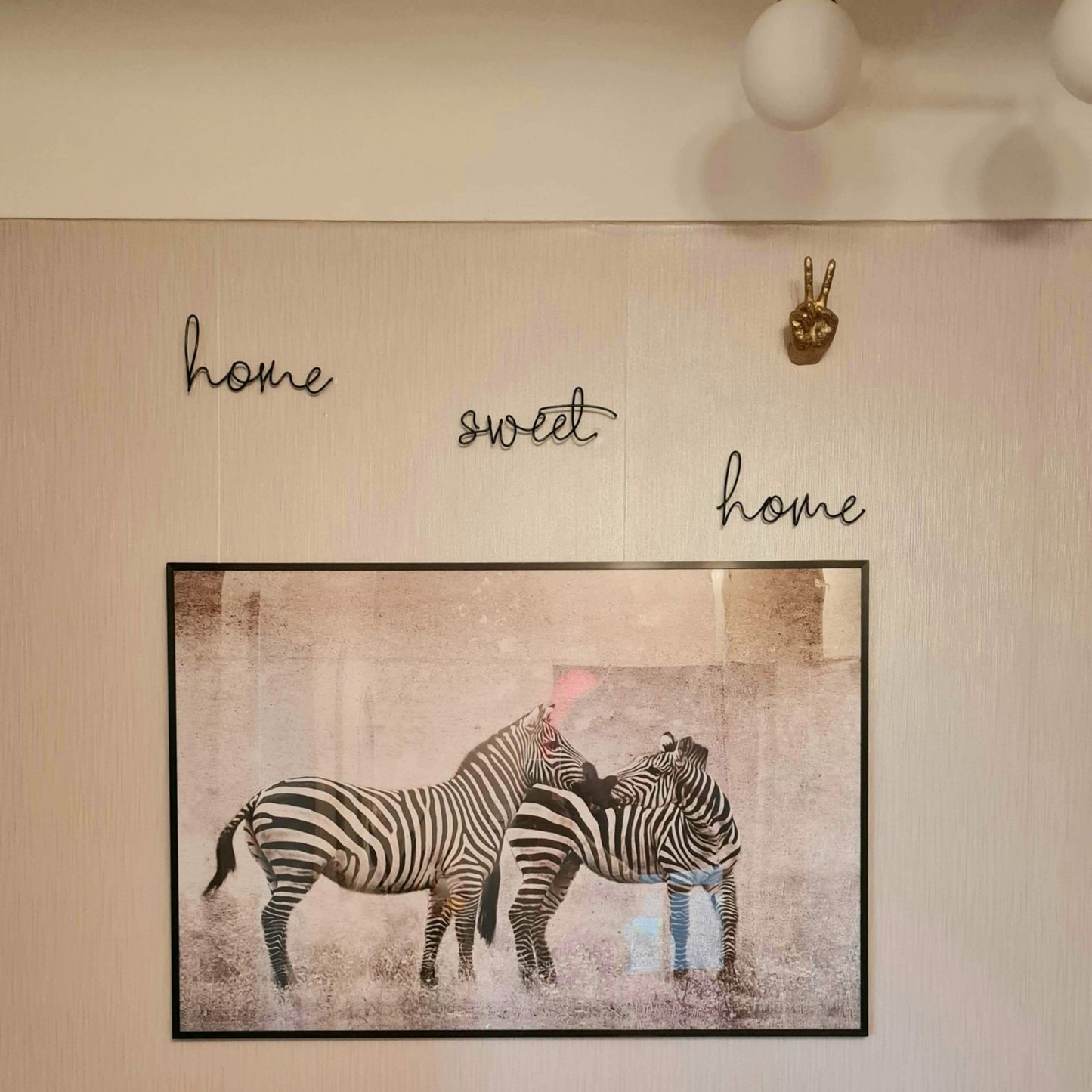 Black Home Sweet Home wire word wall hung on a wall above an art print of Zebras